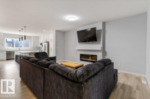 Open-concept living area featuring light wood-finish flooring - 7113 177A Avenue Nw, Edmonton, AB - Indoor Photo Showing Living Room With Fireplace