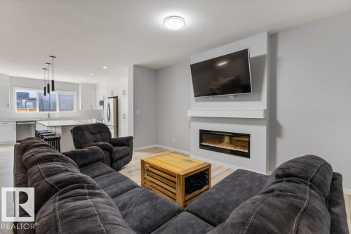 Open concept living area featuring wood-finish flooring - 7113 177A Avenue Nw, Edmonton, AB - Indoor Photo Showing Living Room With Fireplace