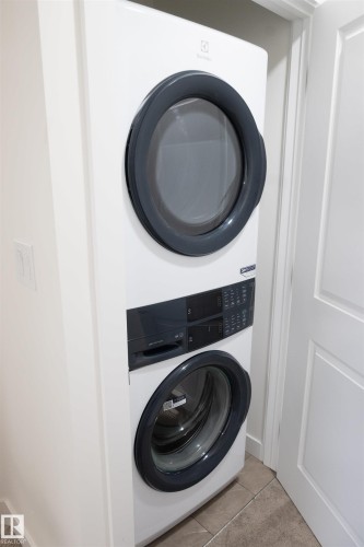 Stackable washer and dryer unit with front-loading design, digital controls, and a tiled floor - #64 2710 66 St Sw Sw, Edmonton, AB 
