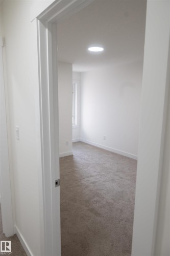 Recessed lighting, neutral-toned carpet, white walls, and a window providing natural illumination - #64 2710 66 St Sw Sw, Edmonton, AB 