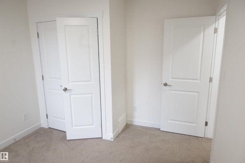 White paneled doors with brushed nickel hardware, light-colored carpeting, and white wall finishes - #64 2710 66 St Sw Sw, Edmonton, AB 