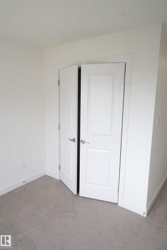 Plush carpet flooring, neutral paint palette, and white paneled bifold doors - #64 2710 66 St Sw Sw, Edmonton, AB 