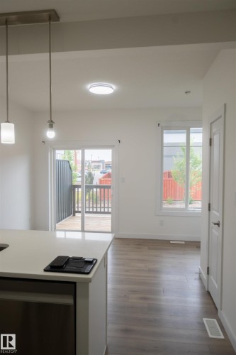 Contemporary kitchen island with a light-toned countertop, integrated dishwasher, and pendant lighting - #64 2710 66 St Sw Sw, Edmonton, AB 