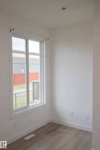 White walls with wood-finish flooring and a large window - #64 2710 66 St Sw Sw, Edmonton, AB 