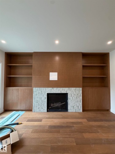 Wood-finish flooring, built-in fireplace with tile surround, recessed lighting, built-in open shelving, and built-in cabinetry - 10223 130 Street Nw, Edmonton, AB 