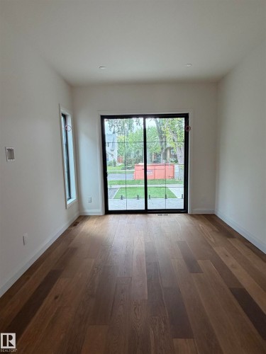 Hardwood flooring throughout, recessed lighting, and a large sliding glass door with black framing - 10223 130 Street Nw, Edmonton, AB 