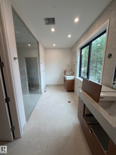 Contemporary bathroom featuring a spacious glass-enclosed shower, light-toned tile flooring, recessed ceiling lighting, and a large window - 10223 130 Street Nw, Edmonton, AB 