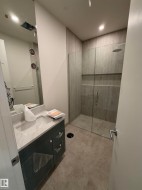Vanity with a light-toned countertop, under-mount sink, and dark cabinetry - 