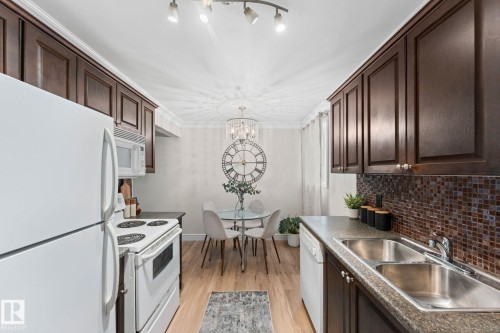 Kitchen featuring dark wood-finish cabinetry, mosaic tile backsplash, and light wood-finish flooring - #106 10735 81 Av Nw, Edmonton, AB 