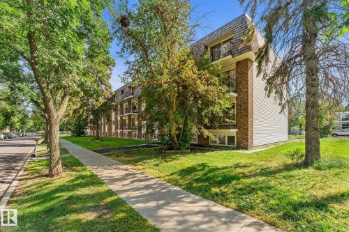 Brick and siding exterior with multiple balconies, a mansard roof, and mature perimeter trees - #106 10735 81 Av Nw, Edmonton, AB 