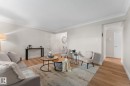 Light-toned wood-finish flooring, crown molding, and neutral wall tones - #106 10735 81 Av Nw, Edmonton, AB 