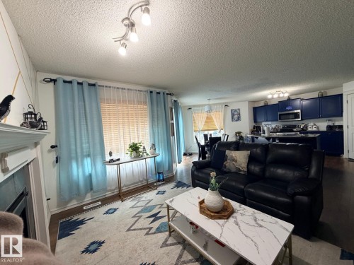 Living area with fireplace, track lighting, and wood-finish flooring - 8715 11 Avenue Sw, Edmonton, AB 