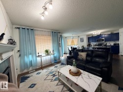 Living area with fireplace, track lighting, and wood-finish flooring - 