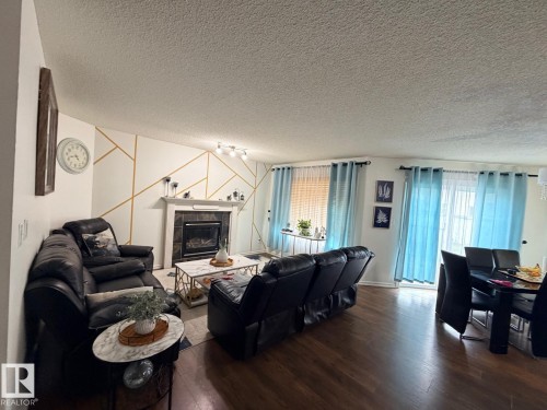 Recessed fireplace with tile surround, wood-finish flooring, and multiple windows providing natural light - 8715 11 Avenue Sw, Edmonton, AB 