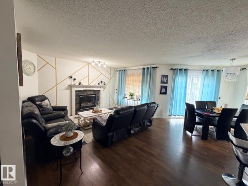 Living area featuring wood-finish flooring and a fireplace with a mantel - 8715 11 Avenue Sw, Edmonton, AB 