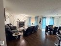 Living area featuring wood-finish flooring and a fireplace with a mantel - 8715 11 Avenue Sw, Edmonton, AB 