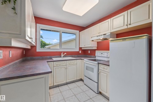 Kitchen featuring white cabinetry with gold-toned hardware, a white drop-in sink, a white electric range, and a white refrigerator - 13320 123 Street Nw, Edmonton, AB - Indoor Photo Showing Kitchen