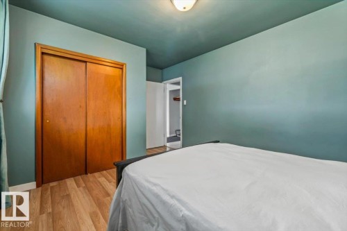 Room featuring wood-finish flooring, a ceiling-mounted light fixture, and a built-in closet with sliding wood doors - 13320 123 Street Nw, Edmonton, AB - Indoor Photo Showing Bedroom