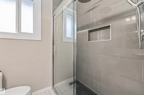 Glass-enclosed shower featuring large format tile, a built-in shower niche, and a rain shower head - 13320 123 Street Nw, Edmonton, AB - Indoor Photo Showing Bathroom