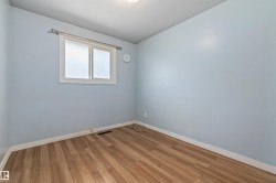 Room featuring wood-finish flooring, light blue walls, and white baseboards - 