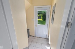 Entryway featuring tiled flooring, a paneled door with a glass insert, and light-colored walls - 