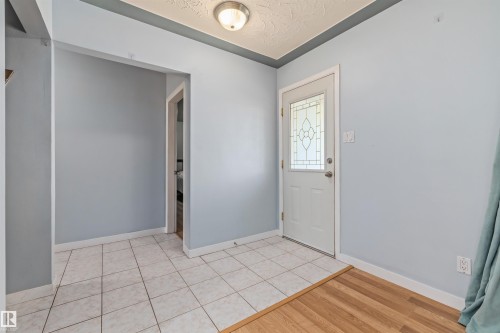 Entryway featuring a decorative glass panel door, light tile flooring, wood-finish flooring transition, and a flush mount ceiling light - 13320 123 Street Nw, Edmonton, AB - Indoor Photo Showing Other Room