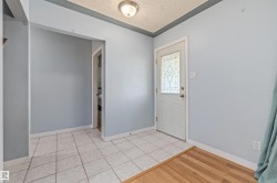 Entryway featuring a decorative glass panel door, light tile flooring, wood-finish flooring transition, and a flush mount ceiling light - 