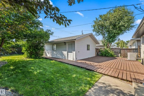 Detached garage with siding exterior, wood-plank deck, and a fenced yard with mature trees and a manicured lawn - 13320 123 Street Nw, Edmonton, AB - Outdoor With Deck Patio Veranda