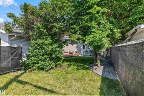 Expansive rear yard featuring mature trees, a manicured lawn, gravel landscaping, and a wooden deck - 13320 123 Street Nw, Edmonton, AB - Outdoor