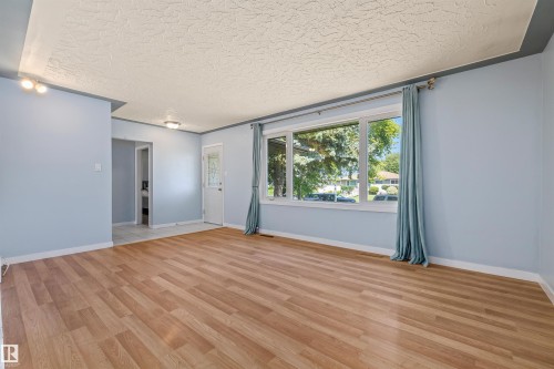 Open-concept room featuring wood-finish flooring, light blue walls, and white trim - 13320 123 Street Nw, Edmonton, AB - Indoor Photo Showing Other Room