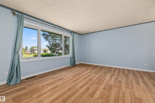 Expansive room featuring wood-finish flooring and light blue walls - 13320 123 Street Nw, Edmonton, AB - Indoor Photo Showing Other Room