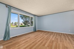 Expansive room featuring wood-finish flooring and light blue walls - 
