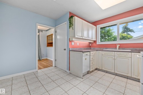 Kitchen featuring white cabinetry, a built-in dishwasher, tile flooring, and a window above the sink - 13320 123 Street Nw, Edmonton, AB - Indoor Photo Showing Kitchen