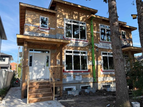 New construction featuring a white front door with sidelights, a covered entry porch, and multiple large windows - 12909 69 Street Nw, Edmonton, AB 