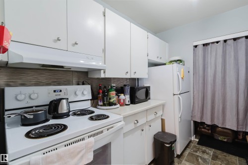 White cabinetry, textured backsplash, white appliances, and a tiled floor - #126 5125 Riverbend Rd Nw, Edmonton, AB 