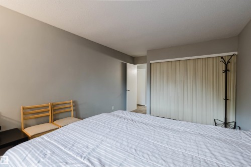Neutral painted walls, textured ceiling, and a full-wall closet with vertical blinds - #126 5125 Riverbend Rd Nw, Edmonton, AB 