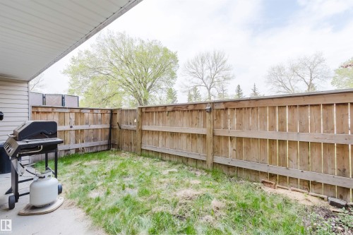Private backyard with wood fencing and a concrete patio area - #126 5125 Riverbend Rd Nw, Edmonton, AB 