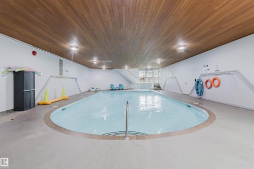 Indoor swimming pool with integrated steps, wood-finish ceiling, perimeter lighting, and neutral-toned flooring - #126 5125 Riverbend Rd Nw, Edmonton, AB 