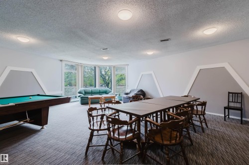 Spacious room featuring curved window wall, recessed lighting, and patterned carpeting - #126 5125 Riverbend Rd Nw, Edmonton, AB 