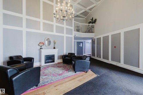 Two-story foyer with coffered ceiling, chandelier lighting, and a prominent fireplace feature - #126 5125 Riverbend Rd Nw, Edmonton, AB 