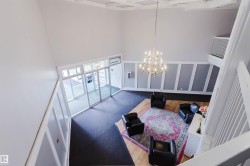 High ceilings with decorative coffered details, classic chandelier lighting, board and batten wall accents, and an expansive glass entryway with transom window - 