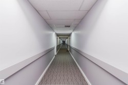 Long corridor featuring drop ceiling, recessed lighting, and patterned carpeting - 