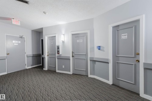 Patterned carpet flooring with gray wall paneling - #126 5125 Riverbend Rd Nw, Edmonton, AB 