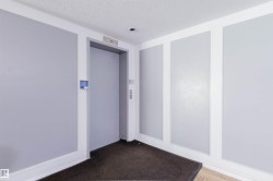 Elevator access with a textured ceiling, recessed lighting, and wall paneling - 