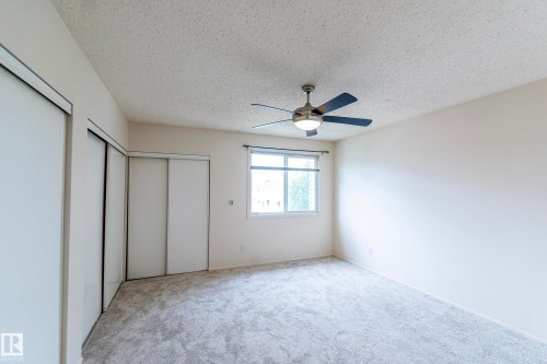 Recessed window, textured ceiling, ceiling fan with integrated lighting, wall-to-wall carpeting, and sliding wardrobe doors - #4 3221 119 St Nw, Edmonton, AB 