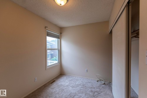 Textured carpet, neutral wall paint, double-pane window, flush-mount ceiling light, and sliding closet doors - #4 3221 119 St Nw, Edmonton, AB 