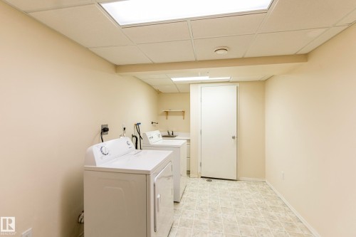 Laundry area featuring tiled flooring, a utility sink, and wall-mounted shelving - #4 3221 119 St Nw, Edmonton, AB 