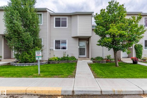 Multi-story exterior with light-toned siding, a concrete walkway, and a manicured lawn - #4 3221 119 St Nw, Edmonton, AB 