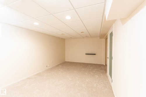 Neutral toned walls, light gray carpeting, recessed ceiling lighting, grid panel ceiling, and a door with frosted glass panels - #4 3221 119 St Nw, Edmonton, AB 