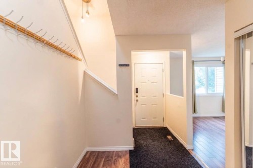 Entryway with wood-finish flooring, staircase, and a front entry door with a multi-pane window - #4 3221 119 St Nw, Edmonton, AB 